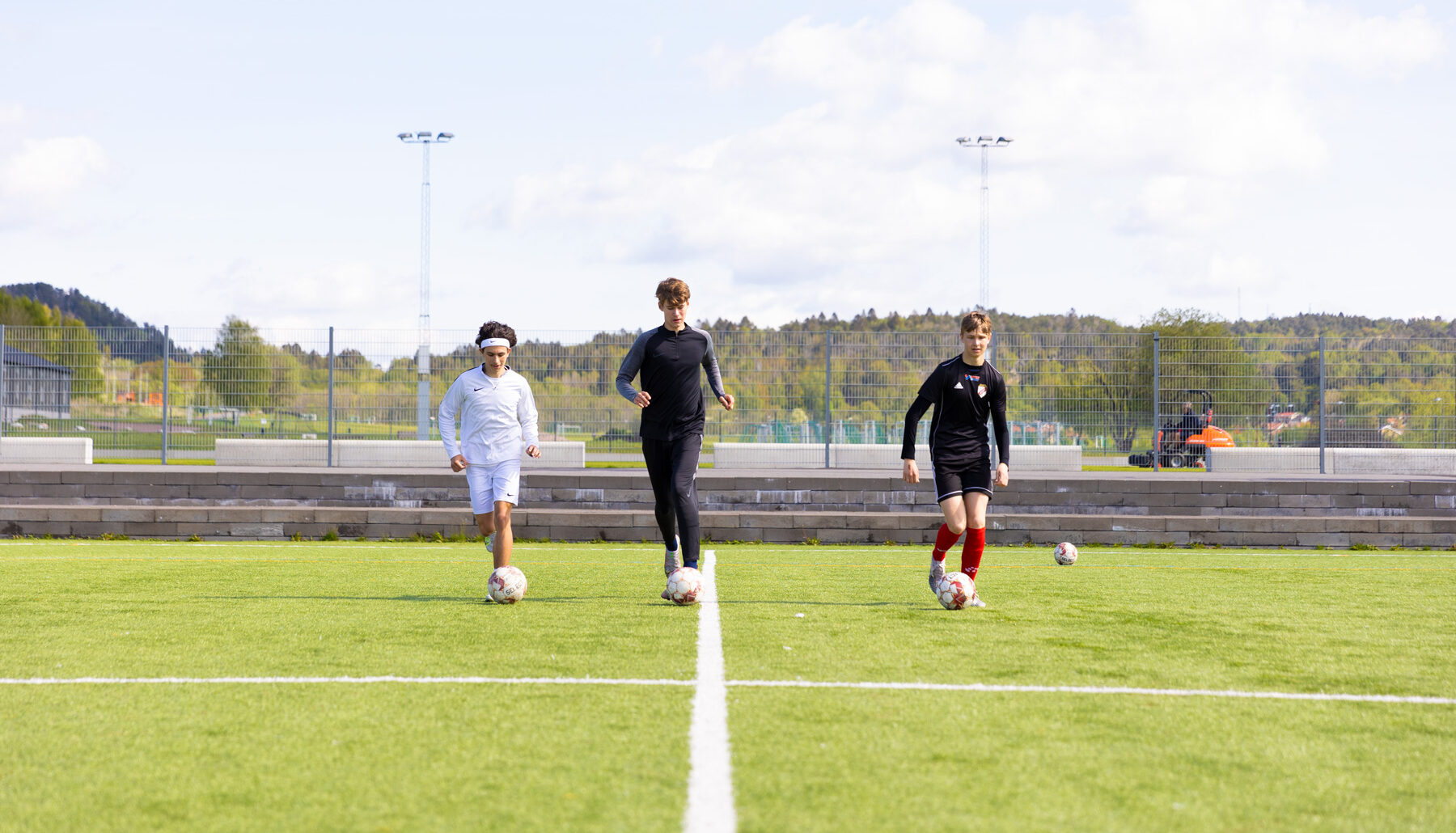 Tre killar som driver boll på en fotbollsplan